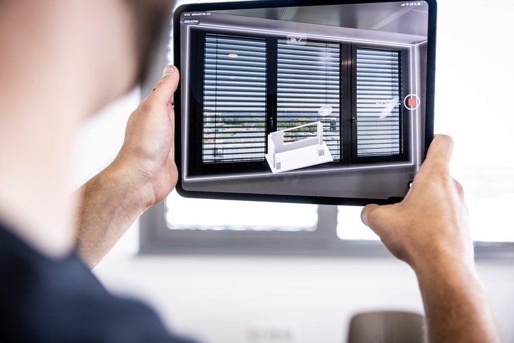 Person scannt mit der Tablet-Kamera ein Fenster mit Jalousien zur 3D-Raumerfassung